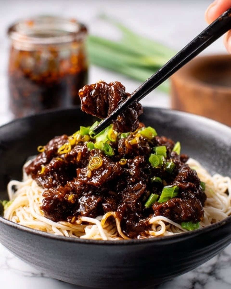 A black bowl filled with a base of thin white noodles at the bottom, topped with a thick layer of dark brown sauce-covered beef pieces mixed with chopped green onions. A pair of black chopsticks held by a woman's hand is lifting some beef from the bowl. In the background, there is a glass jar with dark sauce and a white marbled surface under the bowl. photo taken with an iphone --ar 4:5 --v 7