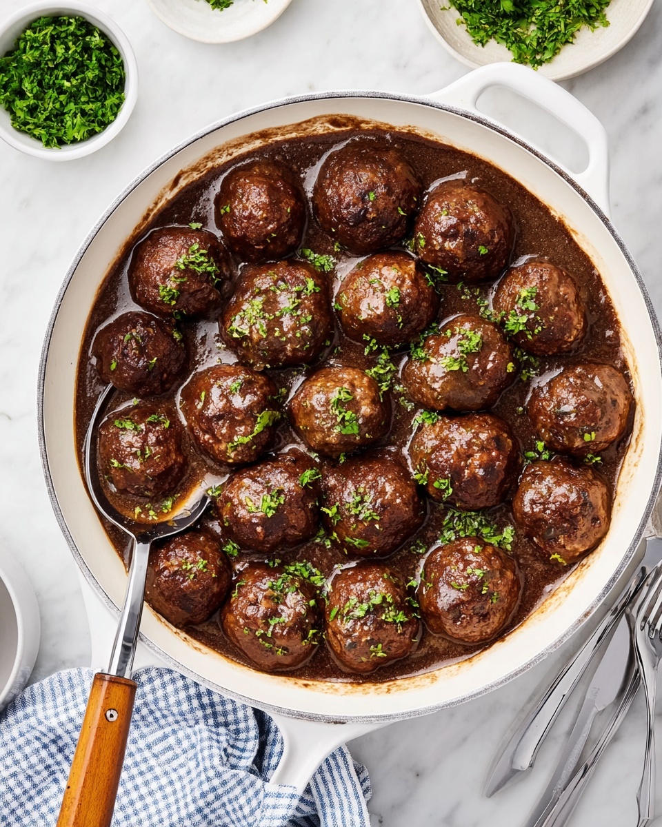 A white pan filled with about twenty brown meatballs arranged in layers with some touching each other, all covered with a dark brown sauce that has a slightly shiny and smooth texture. Light green chopped herbs are sprinkled over the meatballs, adding a fresh contrast. A silver spoon rests inside the pan, partially submerged in the sauce, with the handle extending out over the white marbled surface underneath. In the background, small bowls with chopped green herbs and other ingredients sit on the white marbled table, along with a fork and a blue and white checkered napkin. The photo taken with an iphone --ar 4:5 --v 7