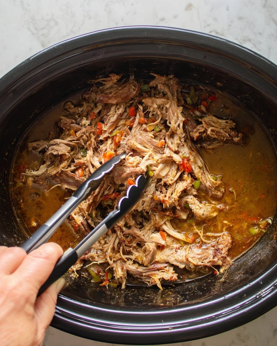 Inside a large black pot, shredded cooked meat with light and dark brown tones is mixed with bits of green and red peppers. The meat sits in a layer of brown broth that glistens with some oil. A woman's hand is holding metal tongs with black tips, lifting a portion of the shredded meat in the center of the pot. The setting is on a white marbled surface. photo taken with an iphone --ar 4:5 --v 7