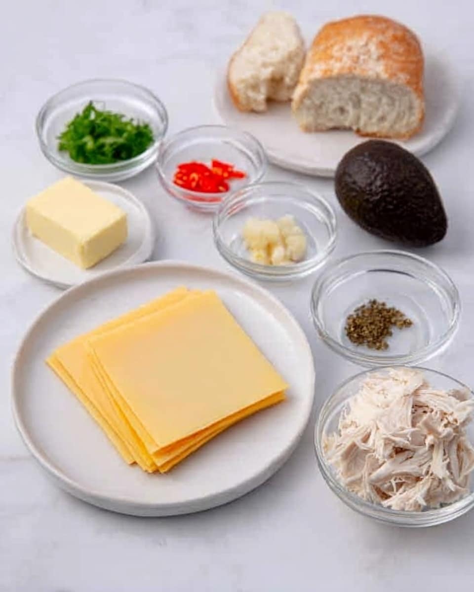 The image shows various ingredients arranged neatly on a white marble surface. There is a whole avocado with dark green, bumpy skin placed next to a round piece of rustic bread on a white plate. In small clear bowls are different ingredients: chopped green herbs, thin strips of red bell pepper, a few dark brown seeds or pods, a small amount of white powder or cream, and a small square of yellow butter in front. A white plate holds three yellow cheese slices stacked evenly. The overall setup is bright with soft, natural light. Photo taken with an iphone --ar 4:5 --v 7