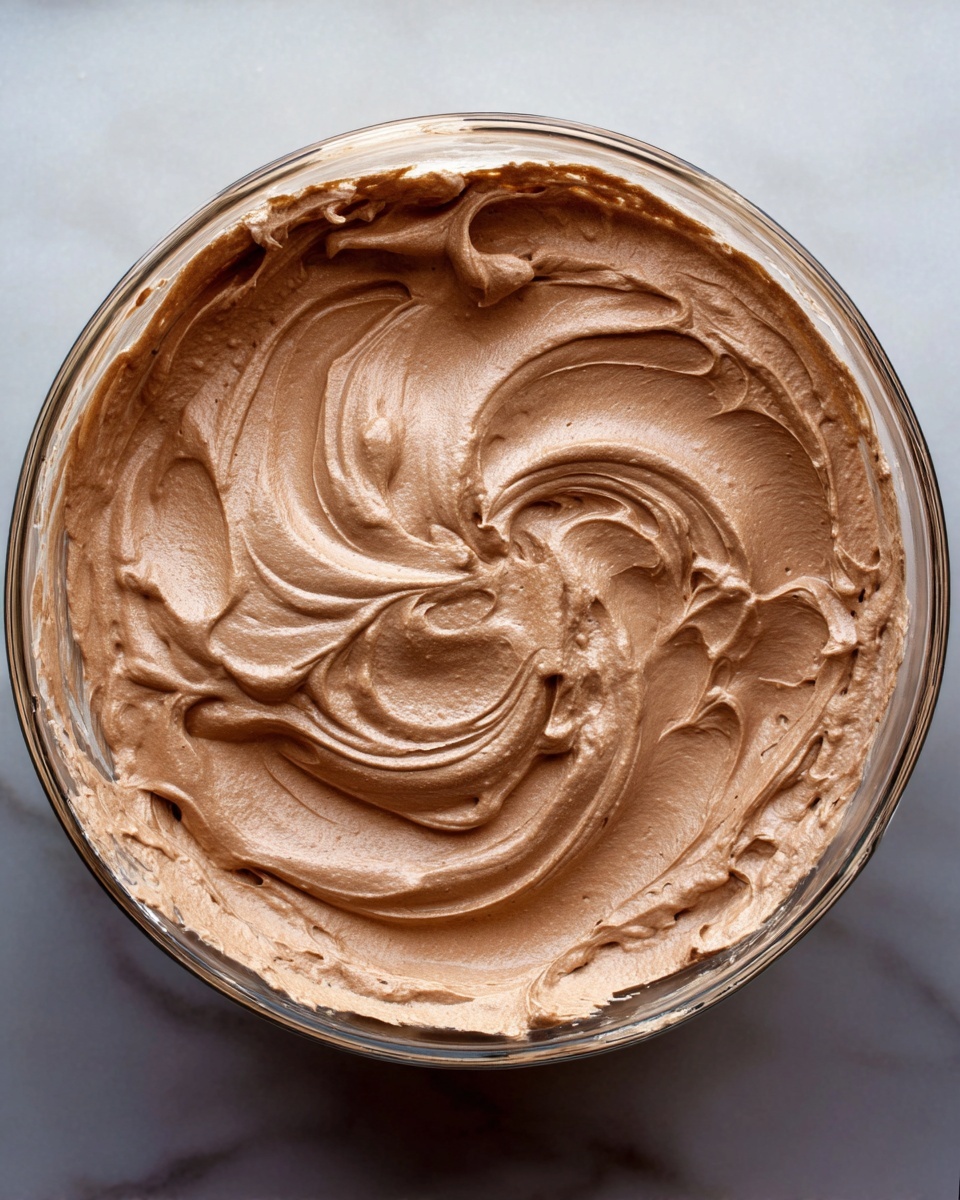 The image shows three clear glass bowls filled with two layers: the bottom layer is dark brown, smooth, and creamy chocolate mousse, and the top layer is a dollop of white whipped cream placed off-center, creating a contrast on the surface. The bowls rest on a wooden surface, with two silver spoons near them. The chocolate mousse in each bowl has a swirled texture creating soft waves, and the whipped cream is slightly textured and fluffy. The focus is on the front bowl, with the other two bowls slightly blurred in the background photo taken with an iphone --ar 4:5 --v 7