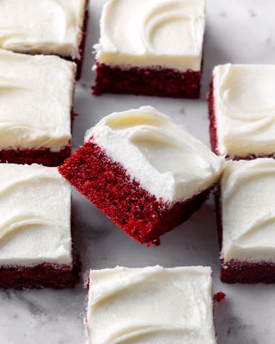 The image shows several square pieces of red velvet cake with smooth white frosting on top. Each piece has two layers: a thick, moist red cake layer at the bottom and a thick creamy white frosting layer on top. The frosting has soft, smooth swirls creating a gentle texture across each square. One piece is positioned at the center, slightly angled to show both the red cake and white frosting clearly. The cake pieces are arranged neatly on a white marbled surface. Photo taken with an iphone --ar 4:5 --v 7