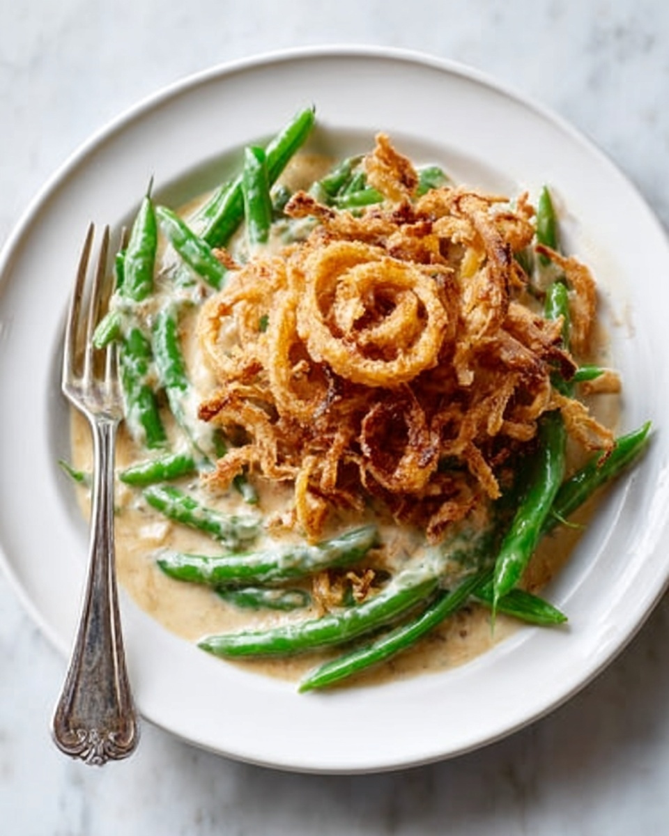 The image shows a close-up of a white oval dish filled with a creamy green bean casserole. The bottom layer is green beans, bright green and slightly crisp. The middle layer is a thick, creamy white sauce coating the green beans evenly. On the top is a golden-brown crunchy fried onion layer, scattered all over and adding texture. A wooden spoon lifts a portion of the casserole, showing all the layers mixing together. The dish is placed on a white marbled surface. photo taken with an iphone --ar 4:5 --v 7