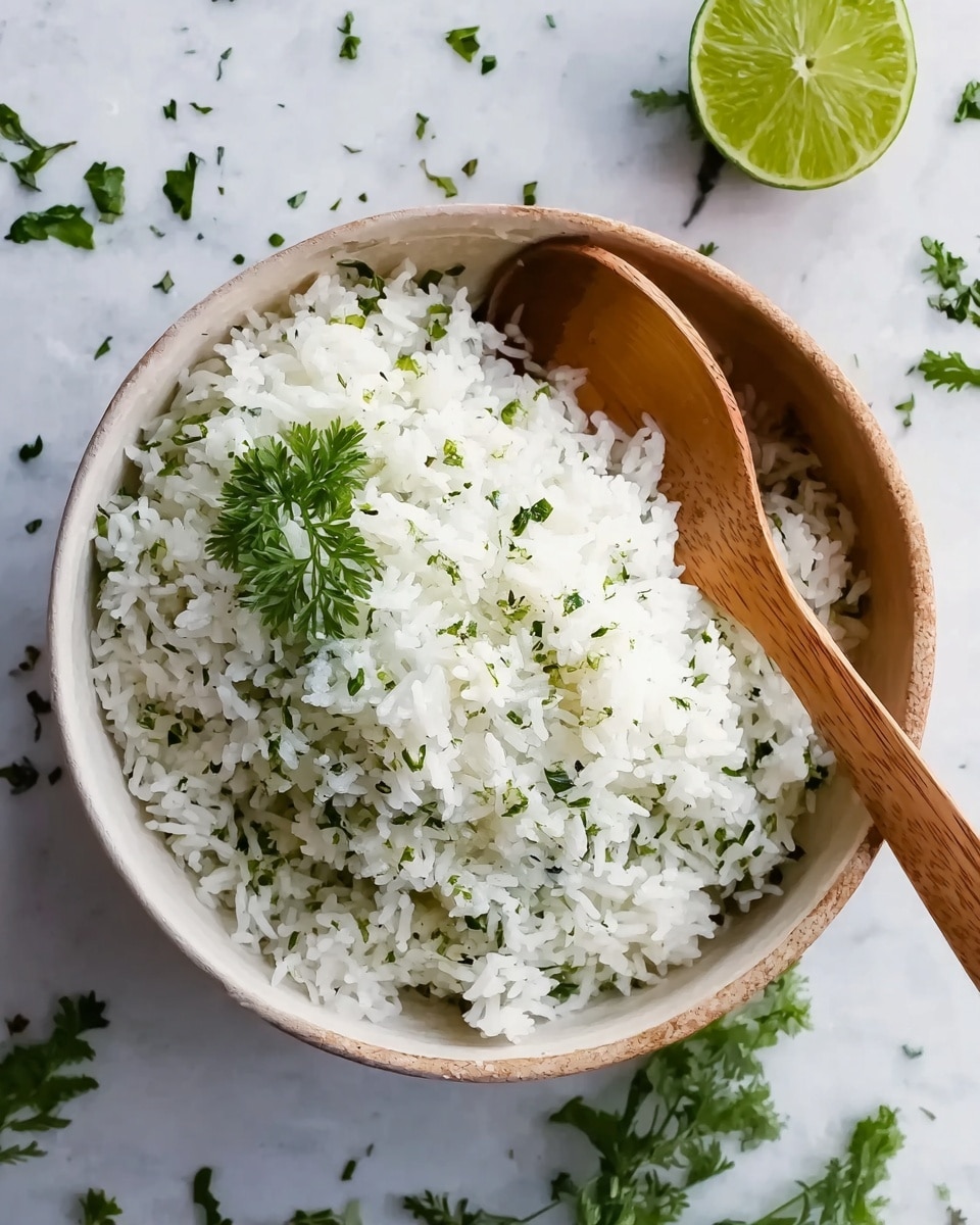 A bowl filled with white rice mixed with small green herb pieces, giving a fresh and light texture. The rice looks fluffy and soft, topped with a small sprig of green herbs on one side. A wooden spoon rests inside the bowl on the right side, angled slightly upward. The bowl is placed on a white marbled surface with scattered green herb leaves around it and a green lime half positioned to the upper right of the bowl. The overall setting is clean and fresh, highlighting the simplicity of the dish. photo taken with an iphone --ar 4:5 --v 7