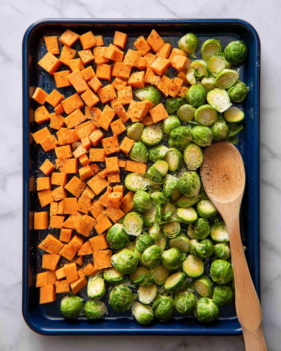 This image shows a dark blue baking tray filled with two layers of vegetables spread evenly. The first layer is made of small, bright orange cubes of sweet potato scattered all over the tray. The second layer consists of fresh, green Brussels sprouts, some whole and some halved, mixed evenly with the sweet potato cubes. A light seasoning of black pepper is visible on the vegetables. On the right side of the tray lies a large wooden spoon resting flat. The tray is placed on a white marbled surface. photo taken with an iphone --ar 4:5 --v 7