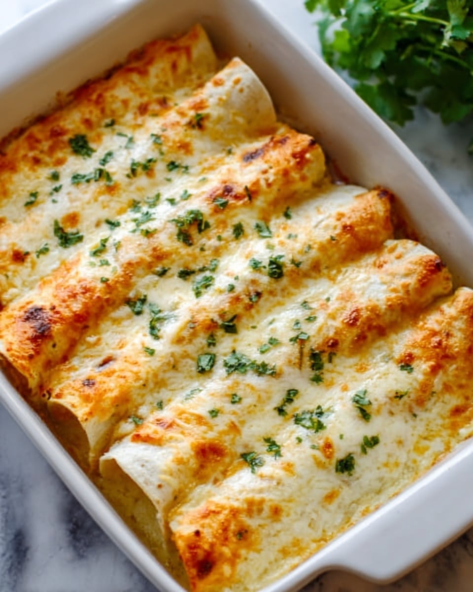 The image shows a white baking dish filled with six rolled enchiladas placed side by side. The enchiladas have a golden-brown melted cheese layer on top, sprinkled with small green herb pieces. The cheese is bubbly and slightly browned in spots, covering the smooth, soft tortilla layers underneath. The filling inside the tortillas is not visible, but the tortillas look soft and well-cooked. The dish is set on a white marbled surface with a blurred green plant in the background. Photo taken with an iphone --ar 4:5 --v 7