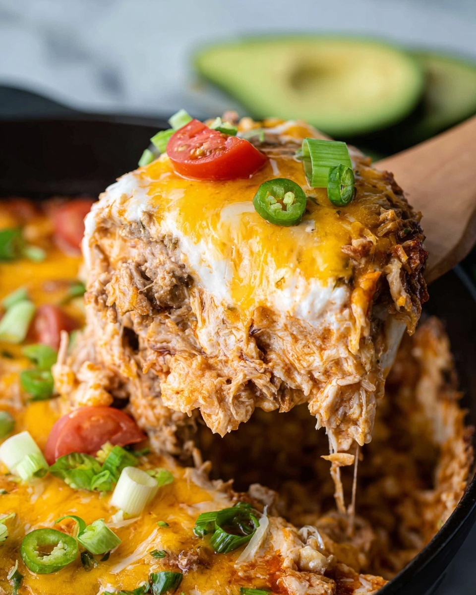 A close-up view of a cheesy baked dish showing a large scoop lifted by a wooden spatula. The dish has multiple layers: a top melted layer of yellow and white cheese with a slightly browned, bubbly texture, fresh green onion slices, and small tomato pieces. Beneath the cheese is a thick layer of shredded light brown meat mixed with a creamy orange sauce. The scoop reveals a firm mashed white layer at the bottom. In the background, there are slices of green avocado and a white marbled surface. The dish is in a black pan. Photo taken with an iphone --ar 4:5 --v 7