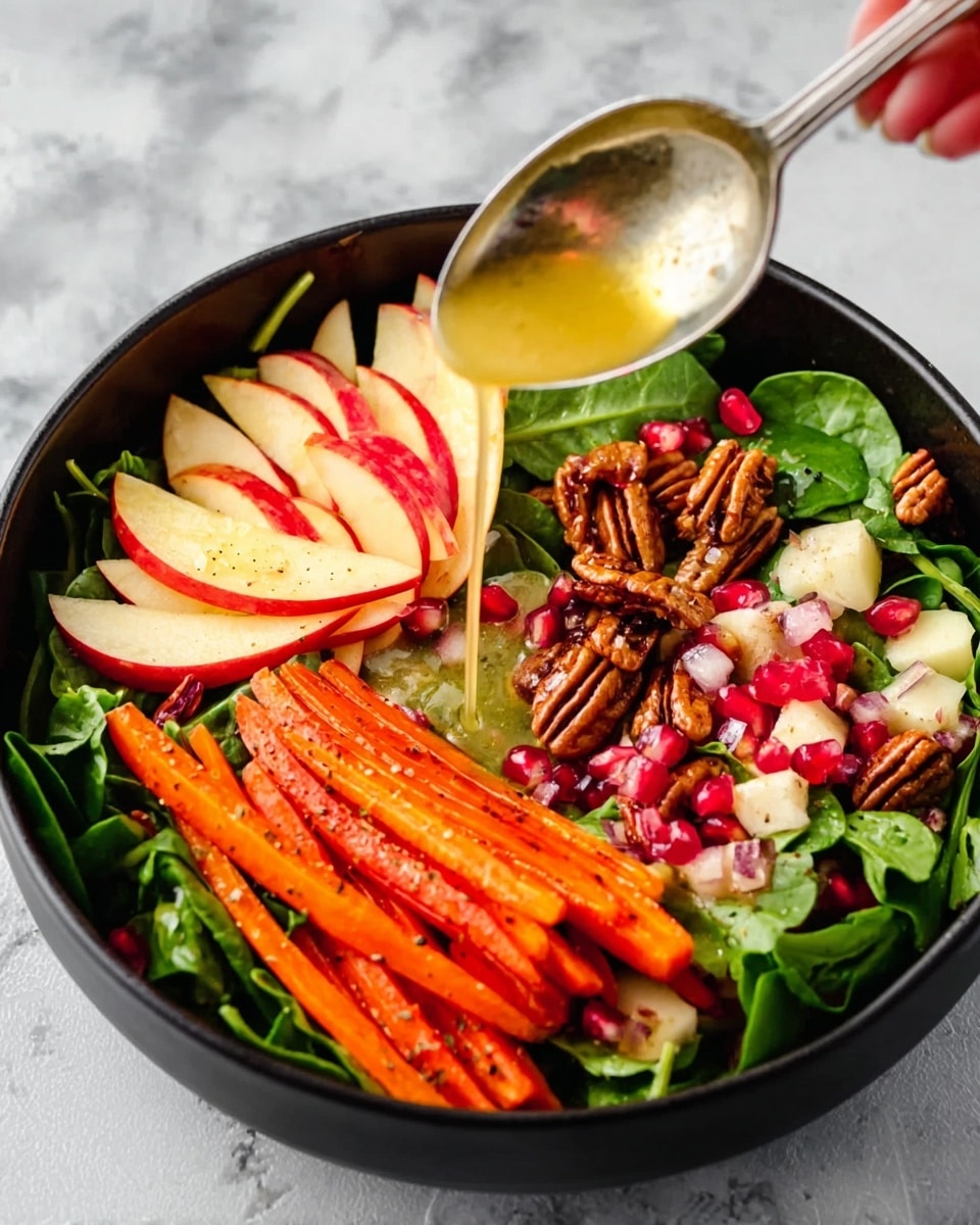 A black bowl filled with a fresh salad on a white marbled surface, containing a base layer of dark green spinach leaves. On top, there are thinly sliced red and light yellow apple slices arranged in a fan shape on one side. Bright orange carrot sticks stand up on another side, with small pieces of chopped pecans scattered around. Next to the apples and carrots, there are small clusters of light pink pomegranate seeds. A silver spoon held by a woman's hand is pouring a golden yellow dressing over the salad. Photo taken with an iphone --ar 4:5 --v 7