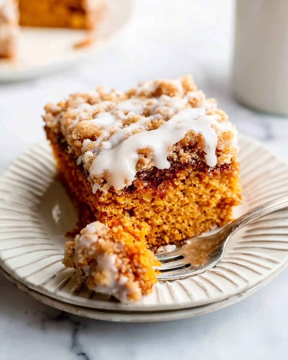 A close-up view of a square piece of crumb cake on a white plate with ridged edges, sitting on a white marbled surface. The cake has two visible layers: the bottom layer is a dense, soft, orange-brown base with a moist texture, and the top layer is a crumbly streusel topping in a golden brown color. There is a white icing glaze drizzled unevenly over the top crumb layer. In front of the cake, a fork holds a small piece of the same base with some crumb topping and glaze. Photo taken with an iphone --ar 4:5 --v 7