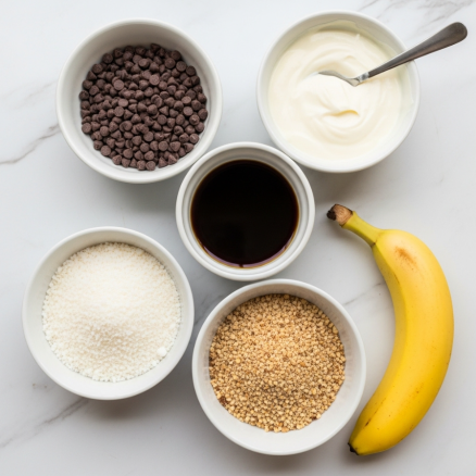 High Protein Frozen Peanut Butter Greek Yogurt Bites Recipe 3 The image shows six white bowls placed on a white marbled surface. The top left bowl contains a pile of dark chocolate chips, the top right bowl holds a smooth, white cream with a spoon inside. The bowl below the cream has a dark liquid, likely coffee or syrup. Beneath the chocolate chips is a white bowl filled with small pieces of white coconut. To the right of the coconut bowl is another filled with small, crushed nuts that are light brown and beige. A ripe yellow banana lies diagonally at the bottom right corner of the image. Photo taken with an iphone --ar 4:5 --v 7