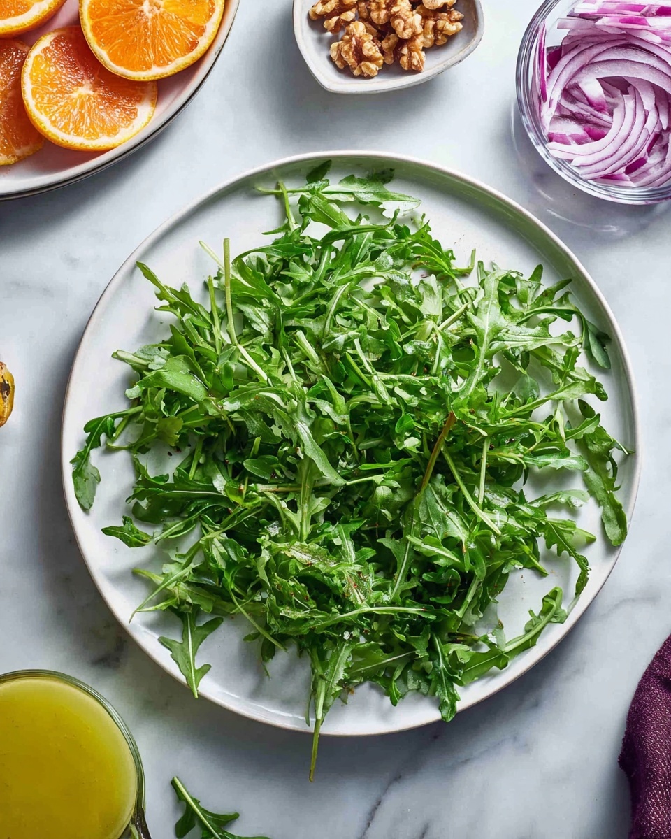 A white plate with a single layer of fresh, green arugula leaves spread evenly, showing their ruffled edges and light veins. Above the plate, there is a white bowl partially visible, filled with slices of dark red and bright yellow citrus fruits. To the right, a small clear bowl contains chopped nuts, some scattered outside the bowl on a white marbled surface. At the bottom right, a glass bowl with thinly sliced light purple onions is partially visible. A small glass bottle with mustard-yellow dressing is also seen on the white marbled surface near the bottom center photo taken with an iphone --ar 4:5 --v 7