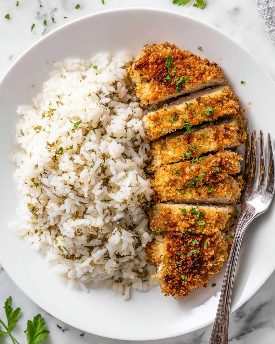 A white plate holds two main layers: on the left is a large portion of cooked white rice with herbs sprinkled on top, showing green and light brown bits, and on the right are several thick slices of breaded food with a golden brown crust that looks crispy, garnished with small green herbs. A silver fork rests on the right edge of the plate, partly on the rice and partly next to the sliced food. The plate is on a white marbled surface with some green herbs scattered around. Photo taken with an iphone --ar 4:5 --v 7