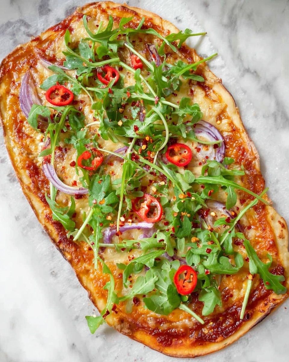 A thin, oval pizza with a golden brown crust sits on a white marbled surface. The first layer is a reddish tomato sauce topped with a light layer of melted, pale yellow cheese. Scattered on top are thin slices of purple onion, bright red chili pepper rings, and fresh, green arugula leaves spread evenly across. Small specks of red chili flakes are sprinkled over the entire pizza, adding a textured contrast. photo taken with an iphone --ar 4:5 --v 7