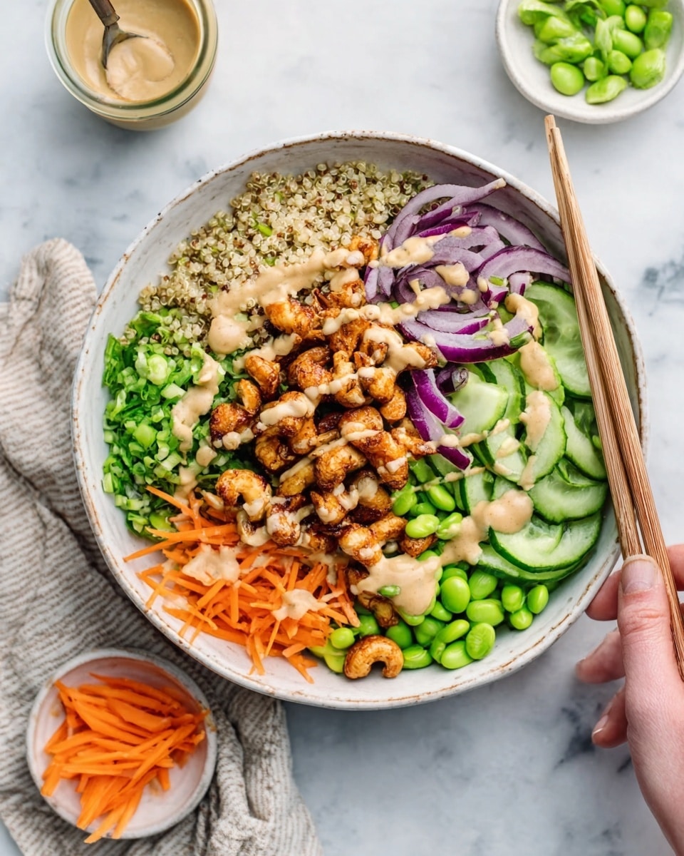 A white bowl on a white marbled surface holds a colorful layered dish. The base layer is light brown quinoa on one side. Next to it, bright green chopped vegetables and whole edamame beans create a fresh look. Thin slices of purple onions form a small cluster, while thin orange carrot sticks make a neat row. Sliced cucumbers add a cool green touch. On top is a creamy beige sauce drizzled over a pile of golden-brown roasted cashews. A woman's hand holds wooden chopsticks resting inside the bowl. Small white dishes with extra edamame and carrots sit nearby. photo taken with an iphone --ar 4:5 --v 7