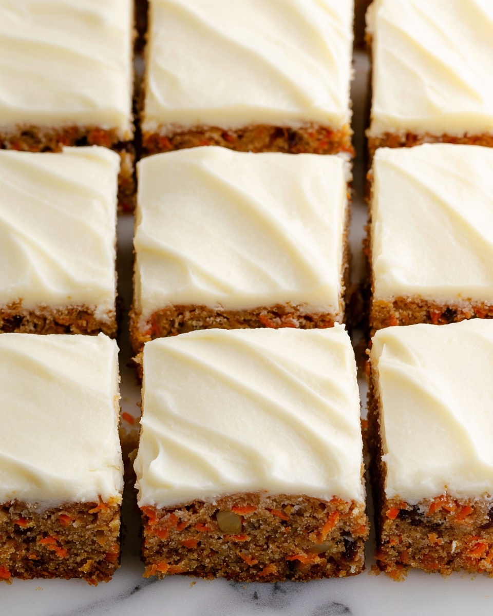The image shows a close-up of a carrot cake cut into nine square pieces arranged in a 3x3 grid on a white marbled surface. Each piece has two visible layers: the bottom layer is a moist carrot cake with visible orange carrot bits and small dark nut pieces, and the top layer is a thick, smooth, creamy white frosting with gentle swirling texture. The pieces are neatly cut, showing clean edges between each square. The photo taken with an iphone --ar 4:5 --v 7