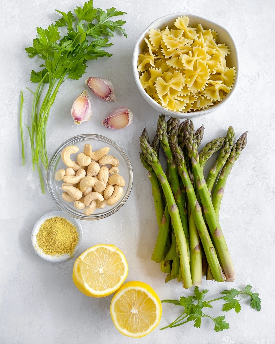 The image shows ingredients arranged on a white marbled surface. There is a bunch of green asparagus stalks placed horizontally in the center. Above the asparagus are three peeled garlic cloves with a light pinkish purple color. To the left of the asparagus, a small clear glass bowl holds pale beige cashew nuts. Next to the cashews is a white bowl filled with yellow farfalle pasta. Below the asparagus, two lemon halves are placed next to each other showing the bright yellow inside. To the right of the lemon, a small white bowl contains a yellow powder, likely nutritional yeast. At the top left corner, fresh green parsley leaves with thin stems are placed. Photo taken with an iphone --ar 4:5 --v 7