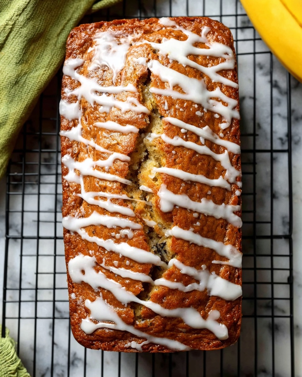 The image shows a rectangular loaf cake with a golden brown crust on a black cooling rack over a white marbled surface. The cake has a rough cracked texture on top with white icing drizzled unevenly in thick lines across the whole surface. The middle crack is more open, revealing a soft inner layer with a lighter, moist texture. There are hints of darker spots inside the cake where ingredients mix, showing some texture contrast. In the background, there is a corner of a green cloth and a yellow banana. photo taken with an iphone --ar 4:5 --v 7