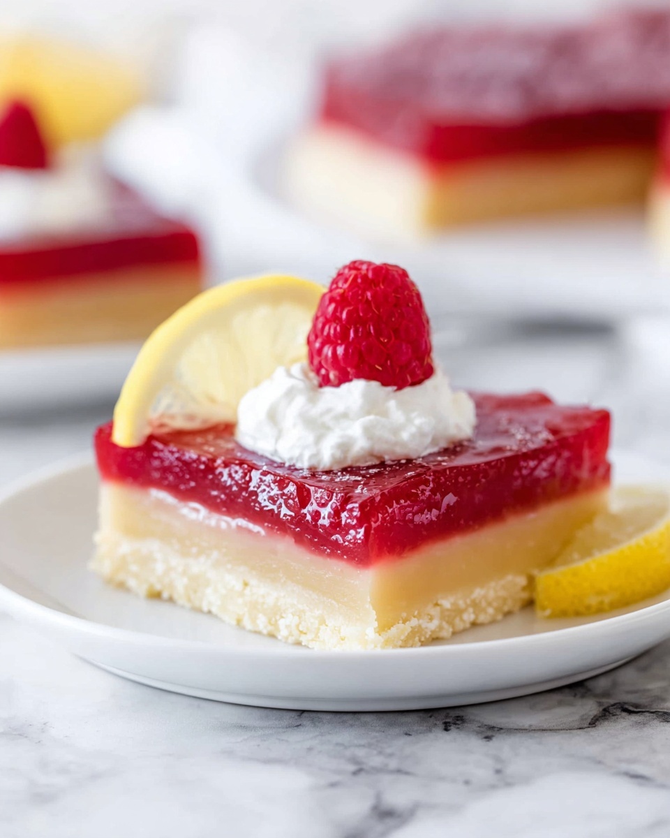The image shows a square dessert bar with two clear layers on a white plate over a white marbled surface. The bottom layer is thick, pale yellow, with a smooth and firm texture resembling a shortbread crust. The top layer is a thick, bright red jam-like filling, smooth with a slight shine and some texture on the edges. On top, there is a dollop of white whipped cream centered on the bar, crowned with a fresh red raspberry and a small thin lemon wedge behind the raspberry. In the blurred background, another plate with similar bars is visible. Photo taken with an iphone --ar 4:5 --v 7