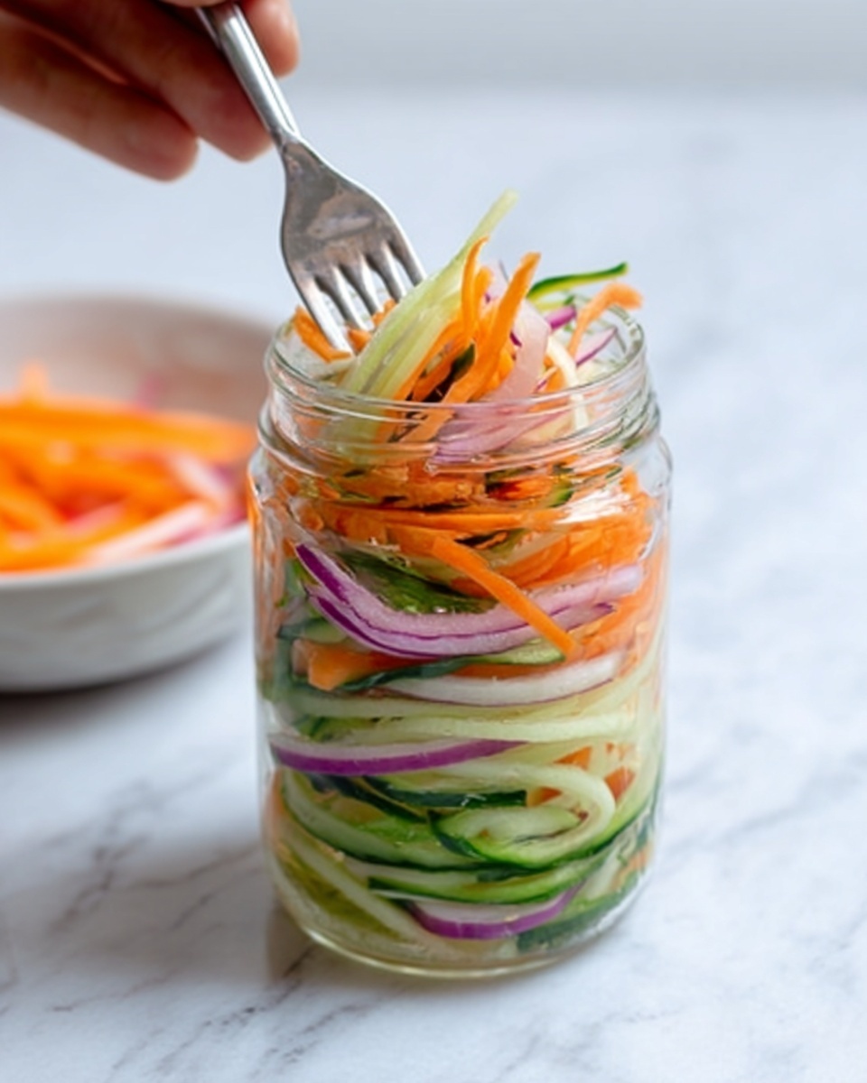 A clear glass jar sits on a white marbled surface, filled with neatly layered thin strips of orange carrot, pale green cucumber, and light purple onion. The vegetables have a fresh, crunchy look with the carrots and cucumbers showing bright, moist textures, while the onions add a soft, crisp detail. A silver fork is inserted into the jar, held by a woman's hand, disappearing into the colorful mix of vegetables. In the background, a white bowl with similar sliced vegetables can be seen slightly out of focus. photo taken with an iphone --ar 4:5 --v 7