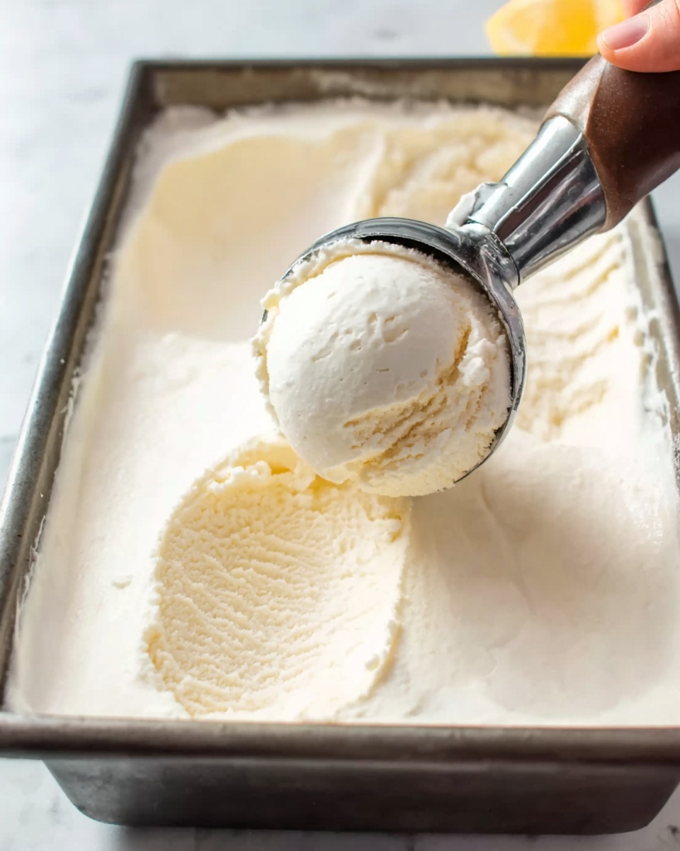 The image shows a metal tray filled with smooth, creamy white ice cream being scooped with an ice cream scooper. The scooper is held by a woman's hand, and a round scoop of ice cream is being lifted, showing its soft texture. The ice cream surface around the scoop is gently uneven, indicating fresh scooping. The background surface is a white marbled texture. Photo taken with an iphone --ar 4:5 --v 7