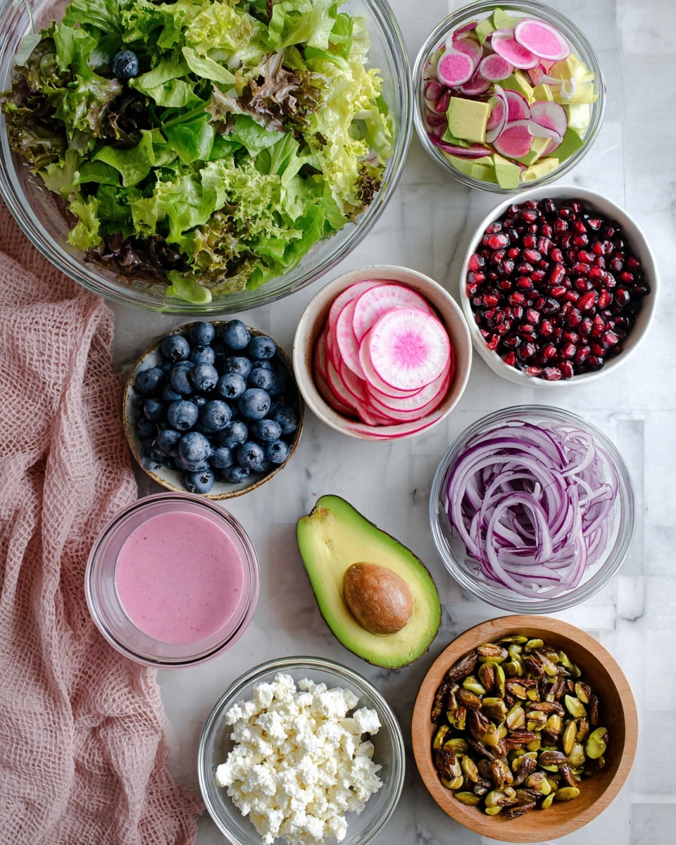 The image shows a top view of various fresh salad ingredients arranged neatly on a white marbled surface. In the center, there is a large clear glass bowl filled with mixed green leafy lettuce. Surrounding it are smaller white bowls holding several layers of vivid blueberries in one, bright red pomegranate seeds in another, thinly sliced pink and green watermelon radish in a few stacked layers in the third, thinly sliced purple onions layered loosely in the fourth, and crumbly white feta cheese in the last bowl. To the right of the bowls, there is a wooden bowl containing caramelized pistachios with a golden brown shine. Next to it, a halved ripe avocado with its smooth green flesh and brown seed is resting on a soft pink cloth. A small glass container filled with pink dressing completes the arrangement on the left side. The overall setup is clean, colorful, and bright. Photo taken with an iphone --ar 4:5 --v 7