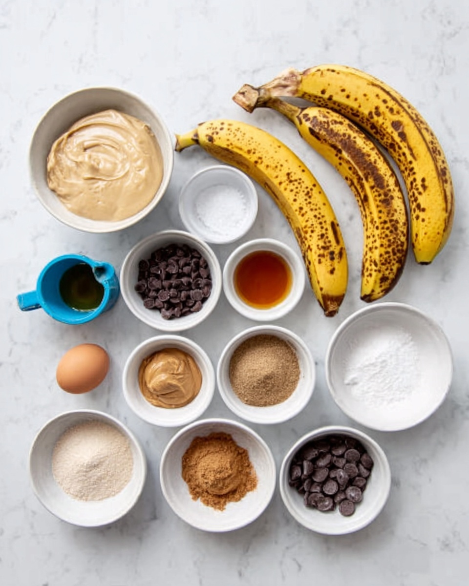 The image shows a white marbled surface with several small white bowls and containers arranged neatly in rows. There are three ripe bananas with black spots in the upper right area. The bowls contain various ingredients: a beige creamy substance in a measuring cup, small dark chocolate chips, light brown cinnamon powder, coarse sugar, light brown peanut butter, and other baking ingredients like vanilla extract and eggs. The layout is clean and organized, with a mix of round bowls and a blue measuring cup. Photo taken with an iphone --ar 4:5 --v 7