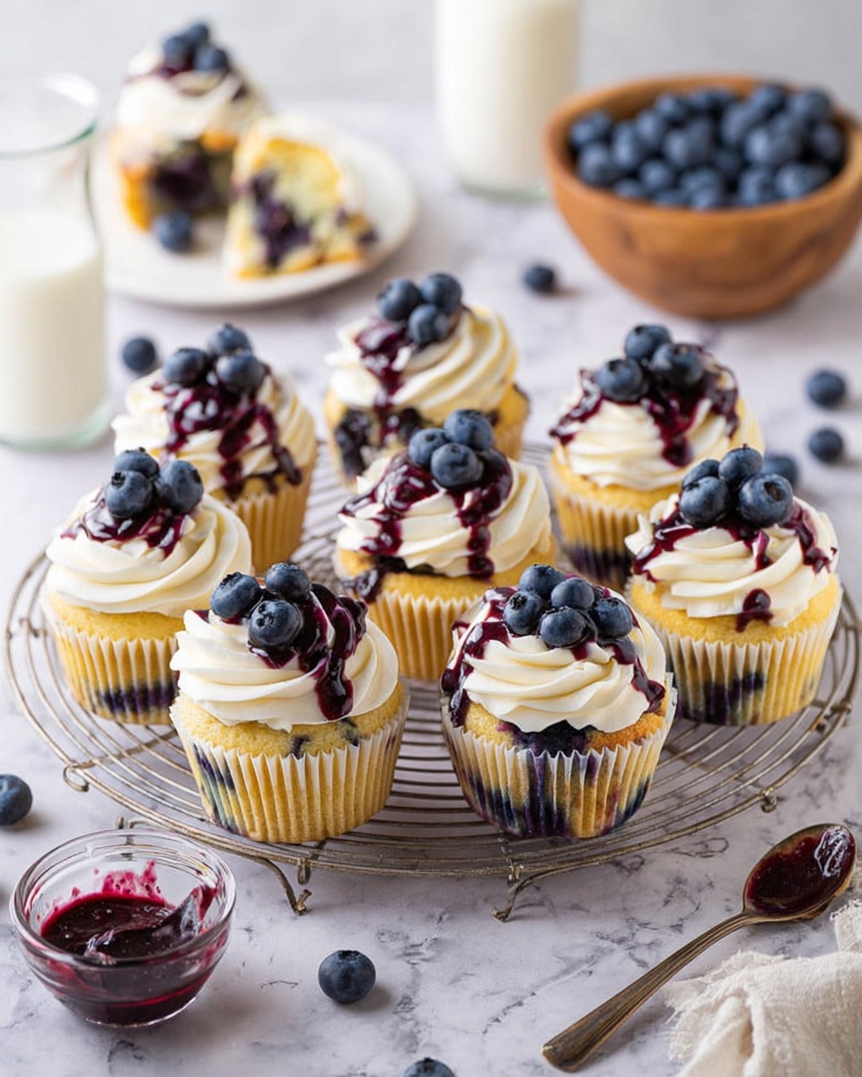 The image shows eight cupcakes arranged on a round wire rack on a white marbled surface. Each cupcake has a yellow base with hints of blueberries baked inside. On top, there is a thick swirl of white cream frosting with dark purple blueberry sauce drizzled over it. Fresh blueberries are placed in small clusters on the top of each cupcake, adding a shiny blue detail. In the background, there is a white plate with a partially eaten cupcake and two glasses of milk. A wooden bowl filled with fresh blueberries and a spoon with blueberry sauce are also visible in the foreground. The photo taken with an iphone --ar 4:5 --v 7