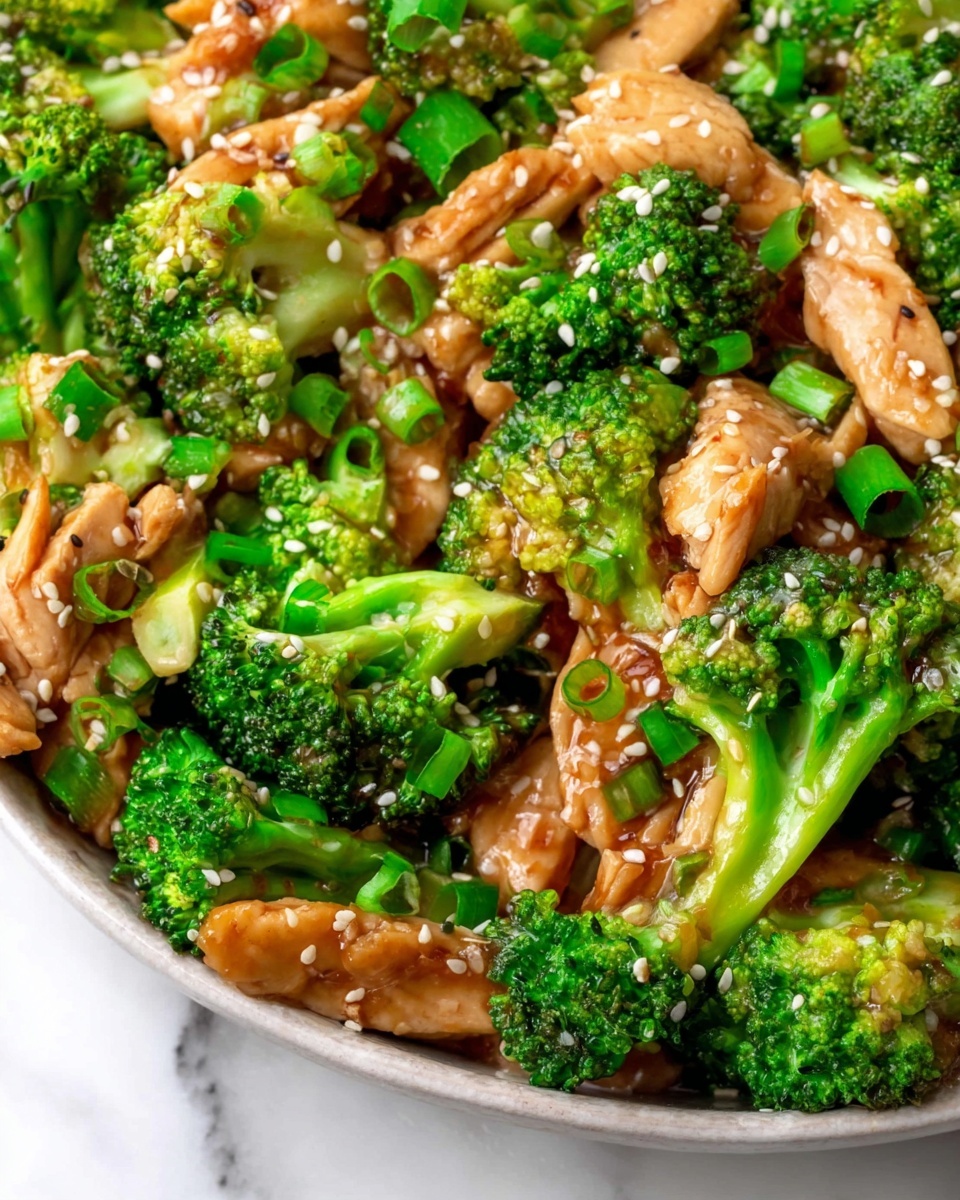 This close-up image shows a dish with three main layers: bright green broccoli florets with a fresh texture, glossy strips of cooked chicken with a light brown glaze, and small white sesame seeds sprinkled evenly on top. Scattered chopped green onion pieces add fresh green color and texture throughout. The dish is presented on a white plate, sitting on a white marbled surface. photo taken with an iphone --ar 4:5 --v 7