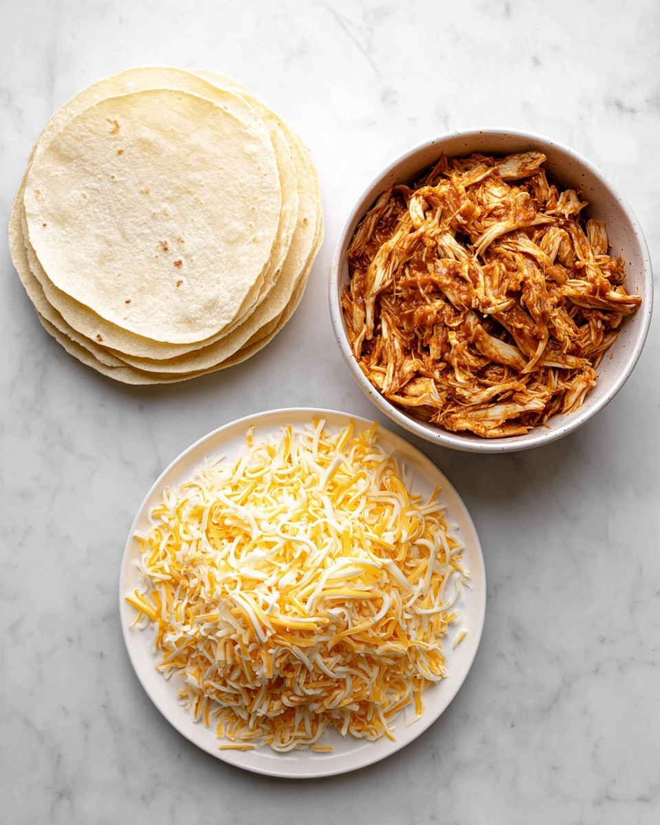 The image shows three white round dishes on a white marbled surface. The top left dish holds a stack of pale, soft corn tortillas with a lightly textured surface. To the right of it is a bowl filled with shredded chicken coated in a reddish-brown sauce, giving the chicken a moist and slightly shiny look. Below these two dishes is a plate heaped with shredded yellow and white cheese, showing a mix of both colors in thin strips. The setup looks clean and fresh with the ingredients neatly arranged. photo taken with an iphone --ar 4:5 --v 7