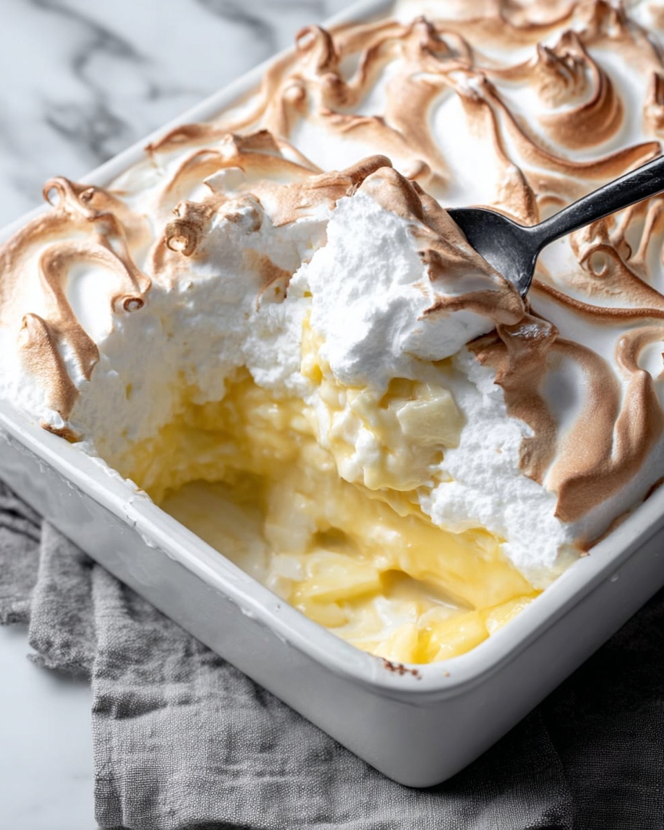 The image shows a white bowl filled with a layered dessert. The bottom layer is a light brown crumbly texture, likely from crushed cookies. On top of that is a thick creamy layer of pale yellow custard or pudding. The custard is covered with big dollops of white whipped cream, which looks fluffy and soft. There are two round light brown cookies placed on one side inside the bowl, partially covered by the cream. Tiny cookie crumbs are sprinkled on the whipped cream, adding some texture. A silver spoon is resting inside the bowl, angled toward the back. The bowl is sitting on a white marbled surface with two similar dessert bowls blurred in the background. Photo taken with an iphone --ar 4:5 --v 7