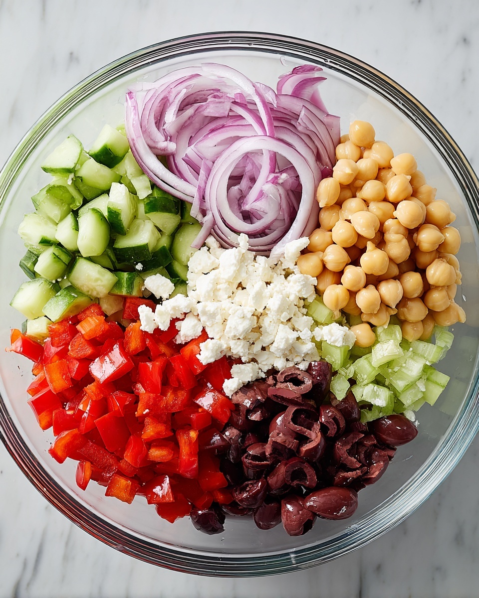 A clear glass bowl filled with six layers of salad ingredients, each arranged clearly and separately in a circular pattern. Starting from the top right going clockwise: pale yellow chickpeas, thin slices of purple-red onion, dark brownish-purple kalamata olives, white crumbled feta cheese, bright green cucumber pieces with pale green centers, and vibrant red diced bell pepper. The bowl is placed on a white marbled surface. photo taken with an iphone --ar 4:5 --v 7