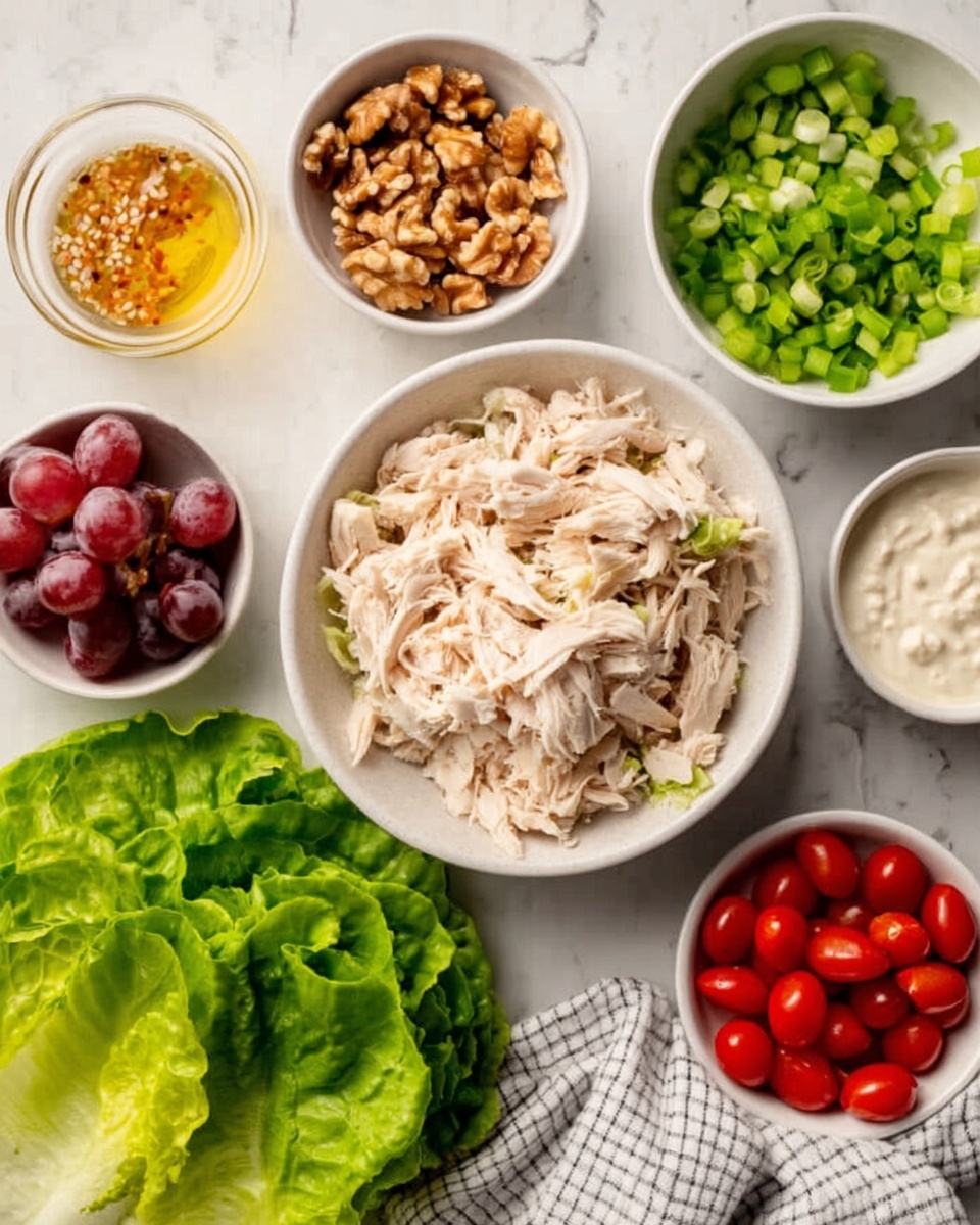 A white bowl with shredded light beige cooked chicken sits in the center, surrounded by smaller white bowls containing bright green chopped lettuce, small green onion slices, red grape tomatoes, a creamy white sauce, chopped brown walnuts, light yellow seasoning, and whole red grapes on the side. A white plate with large green lettuce leaves is visible in the corner, all placed on a white marbled surface with a folded checkered white and gray cloth nearby. photo taken with an iphone --ar 4:5 --v 7