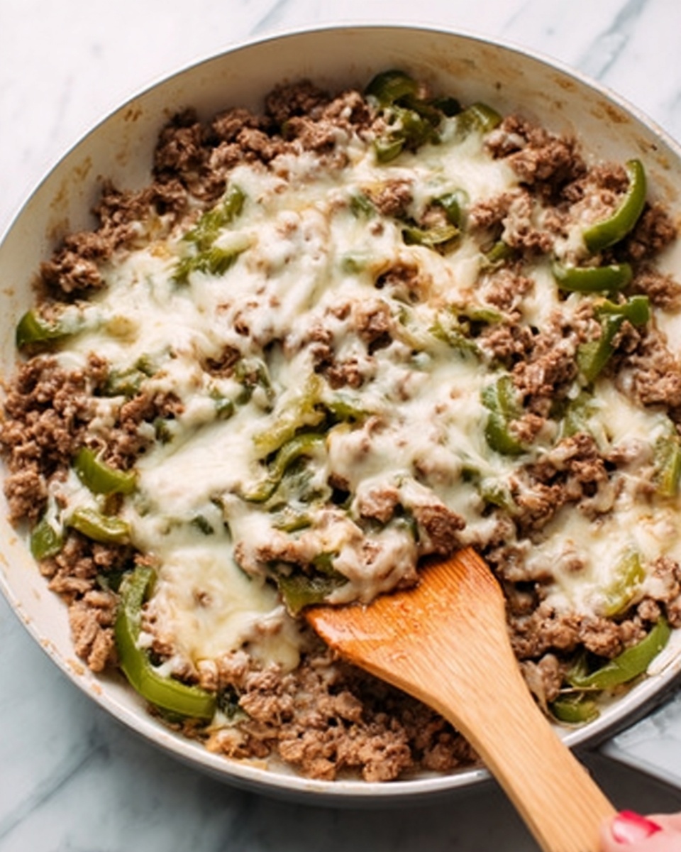 The image shows a white pan filled with cooked ground meat mixed with slices of green peppers and melted cheese on top. The ground meat is brown and crumbly, spread evenly across the pan. The green pepper slices are scattered throughout and add a fresh green color. The cheese is melted and creamy white, sitting on top and blending into the meat and peppers. A woman's hand holds a wooden spatula resting in the pan, partially covered by the ingredients. The pan sits on a white marbled surface. photo taken with an iphone --ar 4:5 --v 7