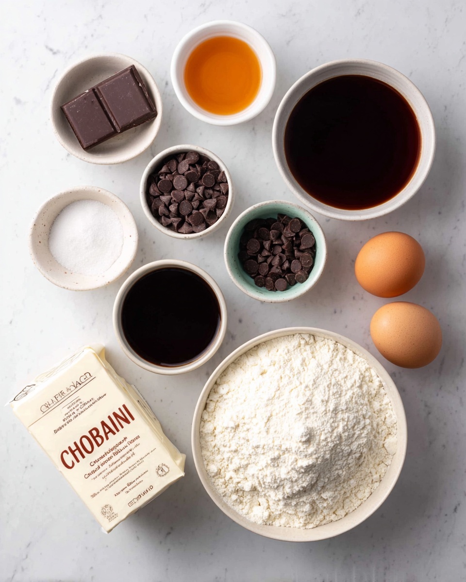 The image shows a top view of various baking ingredients arranged neatly on a white marbled surface. There are small white bowls filled with dark brown liquid, white powder, salt, and small dark chocolate chips. A larger white bowl holds a mound of flour. Two brown eggs sit beside a white container of Chobani Greek Yogurt. Also included is a small rectangular block of butter wrapped in paper. The colors mainly include white and light beige tones with dark brown and orange highlights from the chocolate chips, liquid, and eggs. The setting looks clean and organized with soft natural light. photo taken with an iphone --ar 4:5 --v 7
