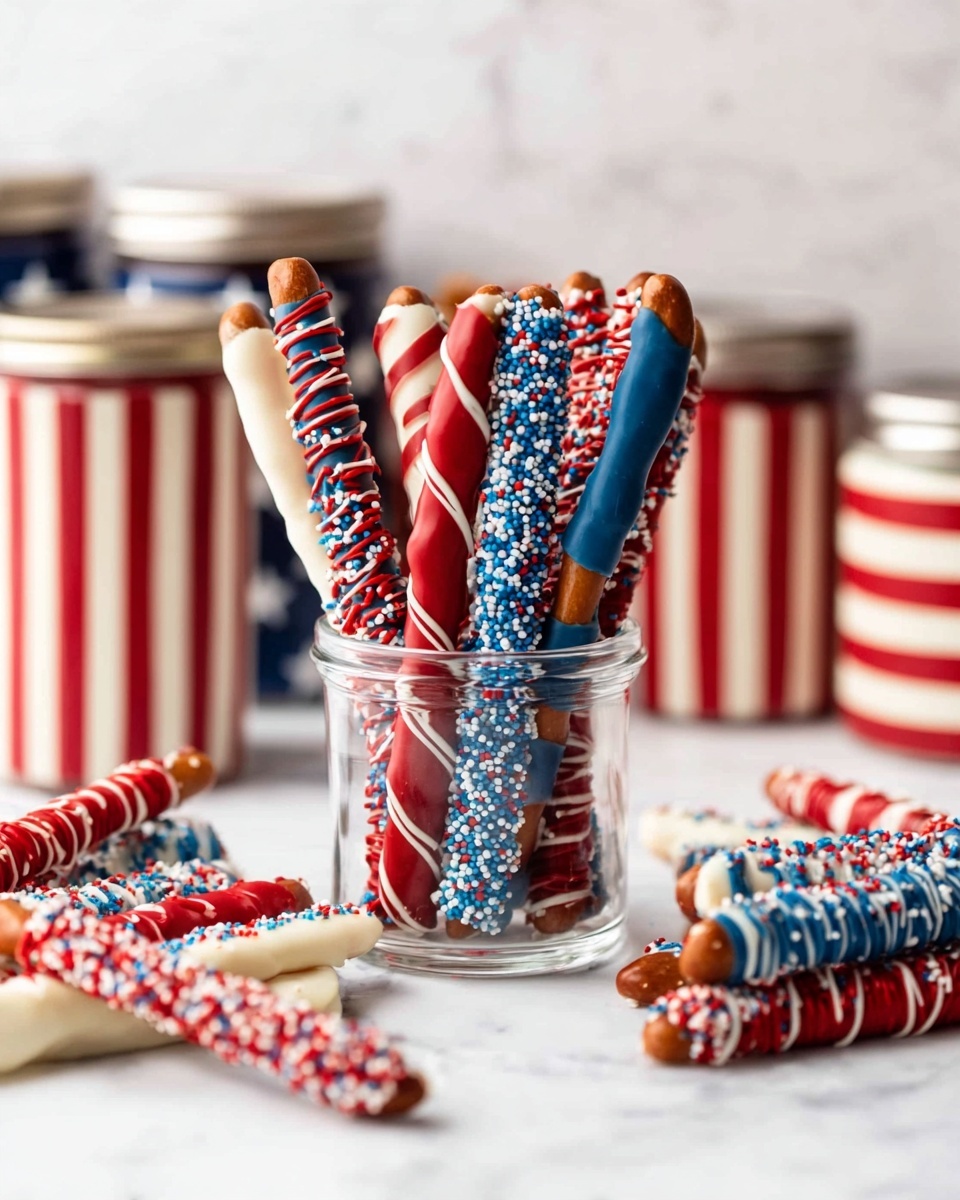 Several pretzel sticks are standing upright inside a clear short glass. Each pretzel is dipped and coated in different layers of red, white, and blue chocolate with smooth and drizzled textures. Some sticks have thin white or red chocolate lines drizzled over a solid base, while others have blue and red sprinkles creating a textured layer on white chocolate. Around the glass, more pretzels lay flat, showing similar colorful patterns with stripes and sprinkles. In the background, there are three jars painted with red and white stripes and blue with white stars, all placed on a white marbled surface. Photo taken with an iphone --ar 4:5 --v 7
