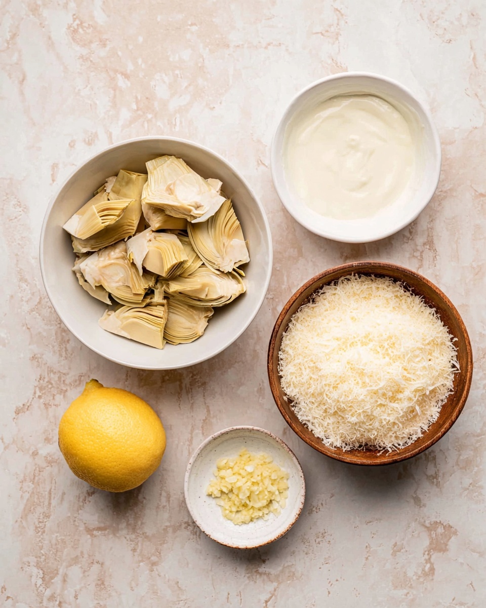 The image shows a simple arrangement of ingredients on a white marbled surface including a white bowl filled with light tan artichoke pieces placed on the top left, a white bowl with creamy white sauce with a smooth texture on the top right, a wooden bowl containing a fluffy pile of grated pale yellow cheese at the bottom right, a small white dish with finely minced light yellow garlic at the bottom left, and a bright yellow lemon half placed near the center bottom. Photo taken with an iphone --ar 4:5 --v 7