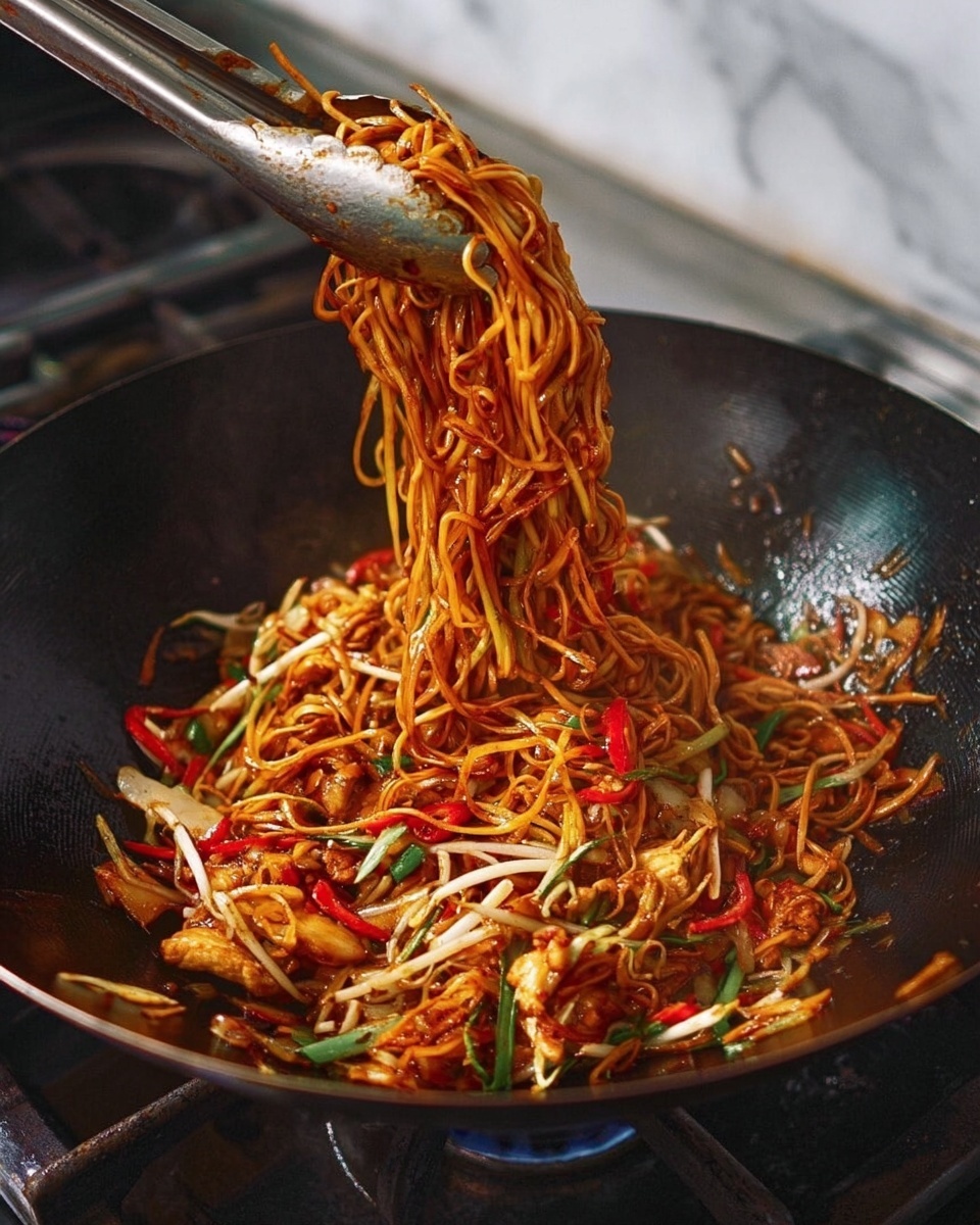 This image shows a black wok filled with stir-fried noodles being lifted with metal tongs. The noodles are long, thin, and coated in a reddish-brown sauce, mixed with slices of red chili, white bean sprouts, small pieces of cooked chicken, and green onion pieces. The noodles have a slight shine, showing they are well-cooked and sauced. The background includes a gas stove under the wok and a white marbled surface. photo taken with an iphone --ar 4:5 --v 7