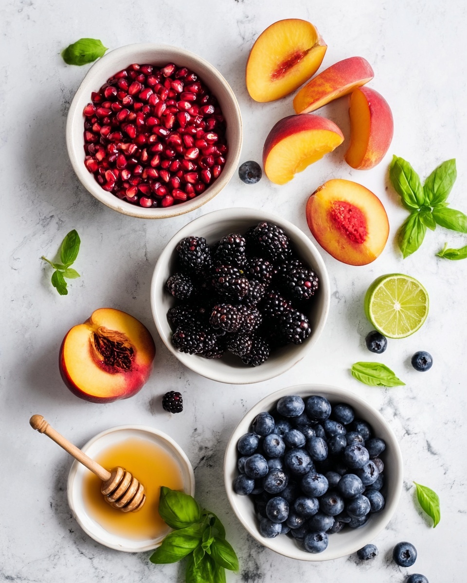 The image shows three white bowls arranged in a loose triangle on a white marbled surface. The top bowl is filled with bright red pomegranate seeds, the right bowl holds dark blackberries, and the bottom bowl contains deep blue blueberries. Around the bowls, there are peach halves with orange-yellow flesh and pits, whole peaches with red and orange skin, a whole red pomegranate, a half lime showing its green segments, and a small white plate with honey and a wooden honey dipper resting on it. Fresh green basil leaves are scattered throughout the composition, adding vibrant green touches. The arrangement is neat and colorful, emphasizing fresh fruit and natural textures. photo taken with an iphone --ar 4:5 --v 7
