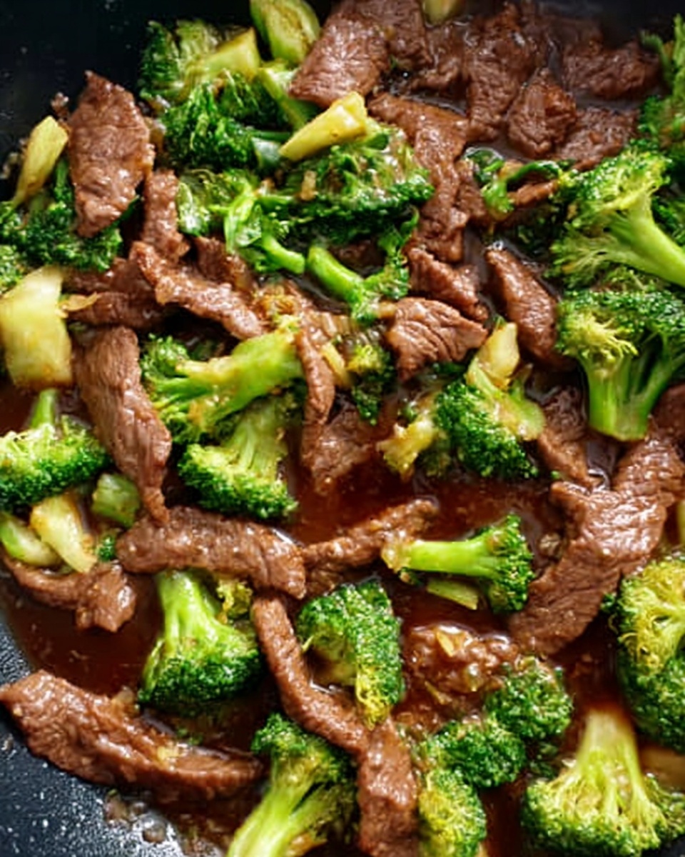 A close-up of a stir-fry dish inside a black pan, showing tender slices of cooked brown beef mixed with bright green broccoli florets. The beef pieces have a slightly shiny, smooth texture, and the broccoli looks soft but fresh with a firm stem and leafy top parts. The sauce is dark brown and coats the beef and broccoli, creating a glossy finish. The stir-fry fills the pan evenly with no separate layers, combining rich, earthy colors of meat and fresh vegetables against the pan's dark surface. photo taken with an iphone --ar 4:5 --v 7