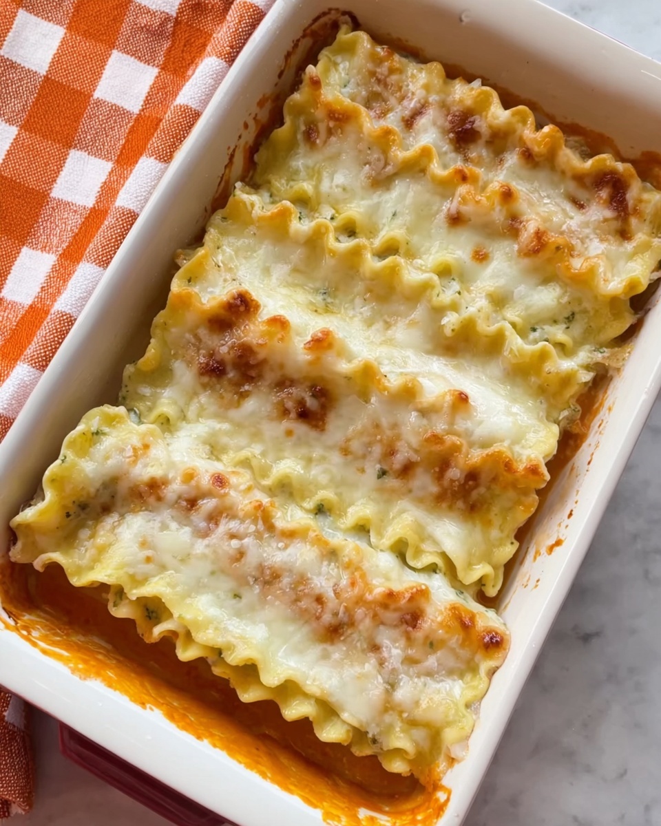 The image shows a white rectangular baking dish filled with two long, layered lasagna pieces placed side by side. The lasagna layers are wavy at the edges, with colors of creamy white and pale yellow with melted cheese on top. The cheese layer looks smooth and slightly browned in spots. The bottom of the dish has some visible orange sauce around the edges, adding contrast. The dish sits on a white marbled surface next to an orange and white checkered cloth. Photo taken with an iphone --ar 4:5 --v 7