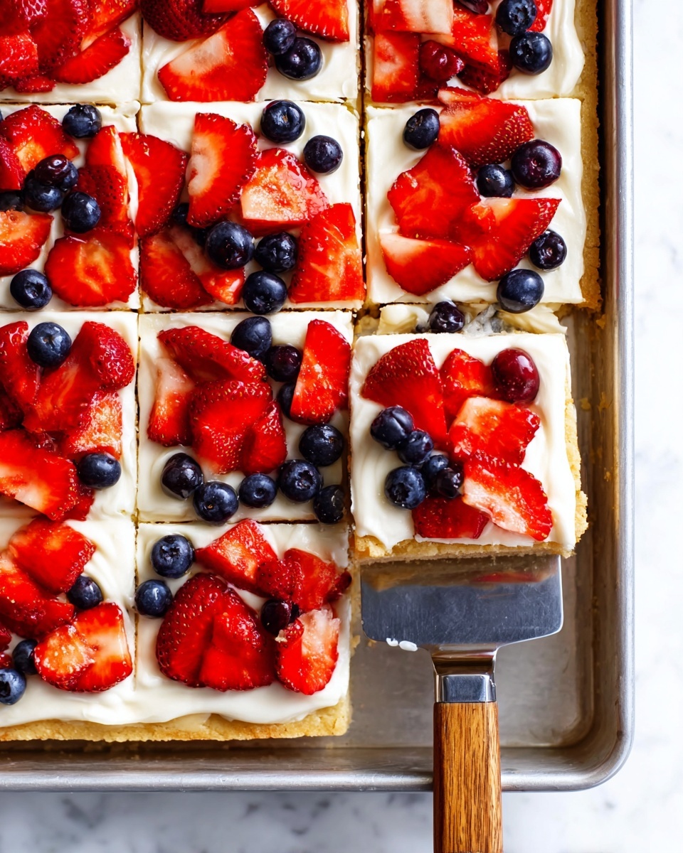 The image shows a dessert cut into nine square pieces, each with three layers. The bottom layer is a golden brown cookie crust that looks firm and slightly crumbly. The middle layer is a smooth, creamy white frosting spread evenly across the crust. The top layer is fresh fruit, with bright red strawberry slices and whole dark blue blueberries scattered over the frosting. One piece in the bottom left is being lifted by a spatula with a wooden handle, revealing the clean layers. The dessert is in a metal pan sitting on a white marbled surface. photo taken with an iphone --ar 4:5 --v 7