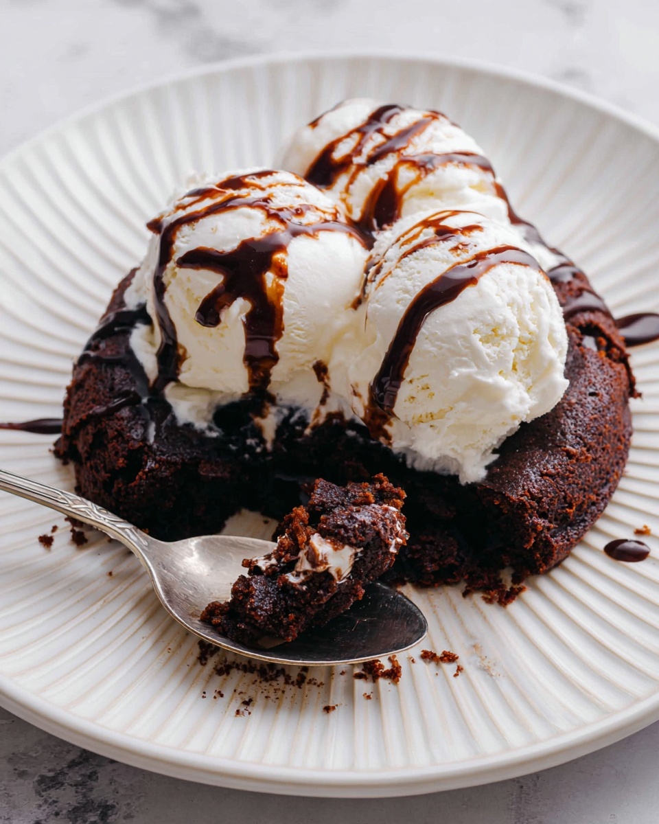 The image shows a dessert served on a white plate with a ribbed pattern placed on a white marbled surface. The base layer is a rich, dark brown chocolate cake with a dense texture, slightly crumbled around the edges. On top of the cake, there are two rounded scoops of creamy white vanilla ice cream with a smooth texture, slightly melting and blending with the cake. Both layers are drizzled with dark chocolate sauce, adding shiny dark streaks over the ice cream and cake. A silver spoon rests on the plate, holding a piece of the chocolate cake with some chocolate sauce on it. photo taken with an iphone --ar 4:5 --v 7