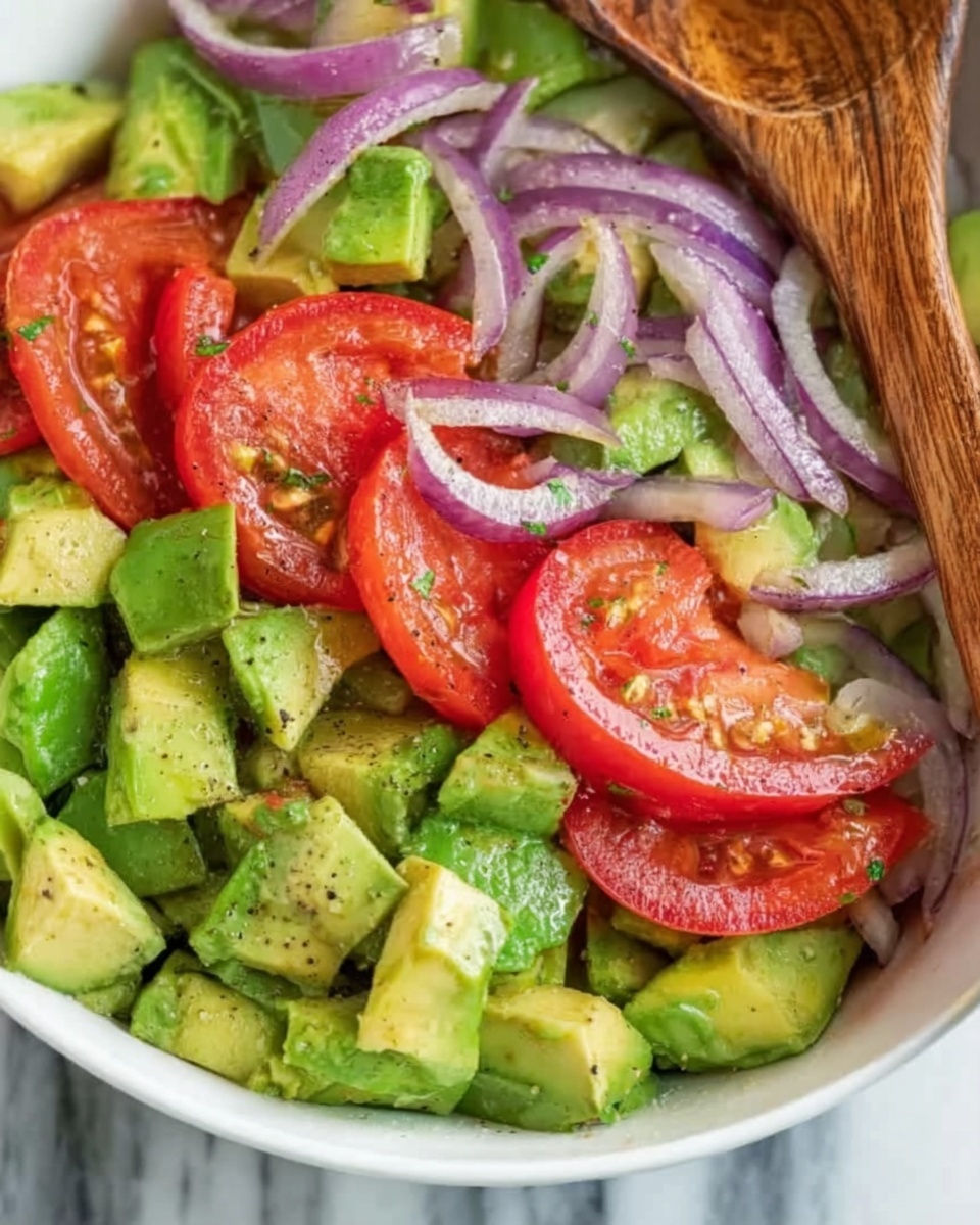 This image shows a fresh vegetable salad with three main layers. The first layer is chopped bright green avocado pieces with a smooth texture. On top of that, there are large slices of red tomato with a juicy look. Scattered among these are thin slices of purple onion, adding color contrast and slight shininess. The salad is in a white bowl, and a wooden spoon is resting on the side, partly visible. The background is a white marbled texture. photo taken with an iphone --ar 4:5 --v 7