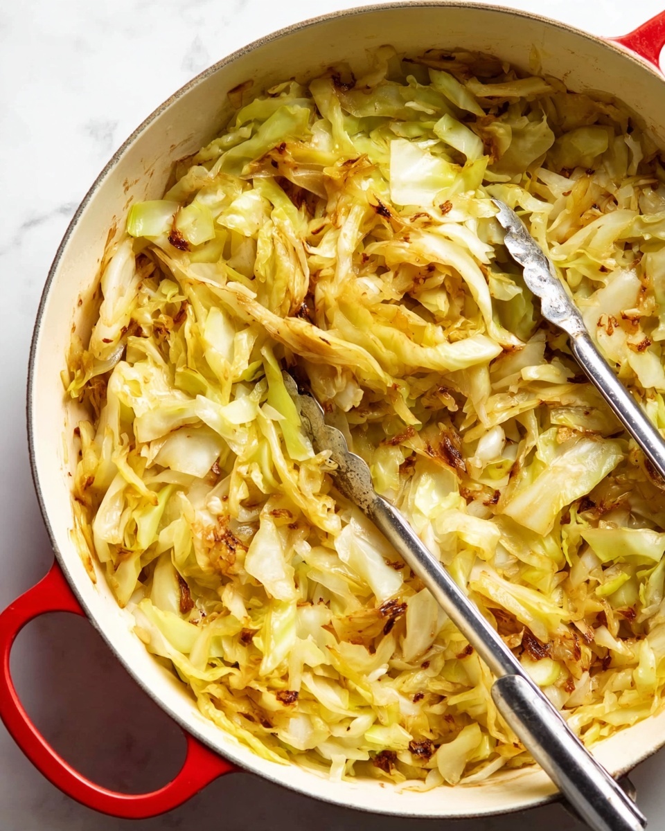 This image shows a close-up of cooked cabbage inside a white pot with a red handle. The dish consists of shredded cabbage layers, light yellow and pale green in color, mixed with bits of browned, slightly crispy pieces throughout. The cabbage appears soft and tender, with some parts having a golden-brown char that adds texture. A pair of silver tongs rests inside the pot, partly lifting the cabbage. The background is a white marbled surface. Photo taken with an iphone --ar 4:5 --v 7