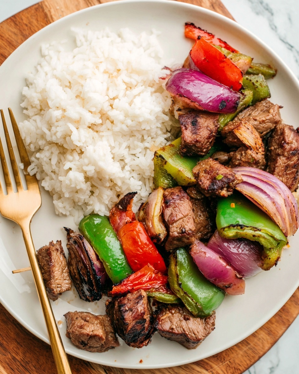 A white plate with two main parts: on the left, a pile of plain white rice with soft, small grains; on the right, a mix of grilled pieces of brown meat, bright green bell peppers, red bell peppers, and purple onion slices. The meat chunks are thick with a slightly charred texture. The vegetables are cut into medium pieces, some with smooth shiny skin and some with rough grilled edges. A gold fork is placed beside the plate on a wooden surface. The background is a white marbled texture, photo taken with an iphone --ar 4:5 --v 7