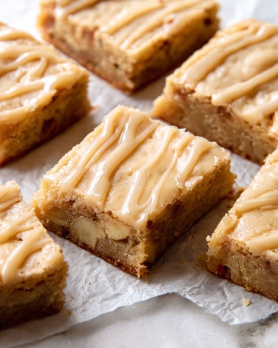 The image shows several square blondie bars with a light golden-brown color and smooth texture on top. Each bar has a layer of creamy, pale caramel-colored icing drizzled unevenly, giving it a soft wavy look. The bars are placed closely together on white parchment paper that covers a white marbled surface. One blondie is slightly raised, showing a dense and soft inside with small chunks of nuts or chocolate. The light highlights the moist and rich texture of the bars. Photo taken with an iphone --ar 4:5 --v 7