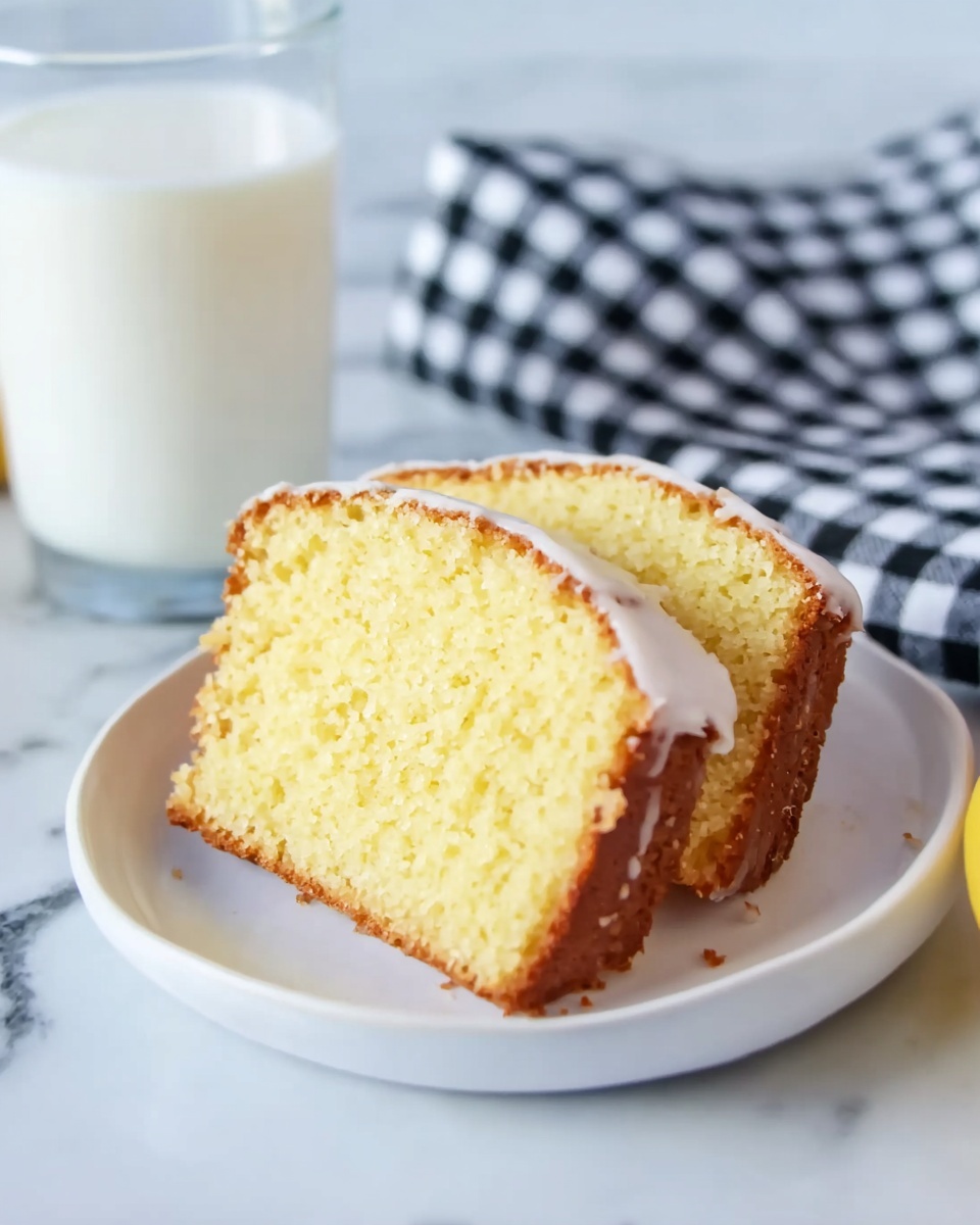 Two slices of yellow pound cake with a light crust are stacked on a white plate. The cake has a soft and crumbly texture, with a thin layer of white icing on one side of each slice. The plate sits on a white marbled surface, and behind it, there is a black and white checkered cloth. To the left, a clear glass filled with milk is partly visible. Photo taken with an iphone --ar 4:5 --v 7