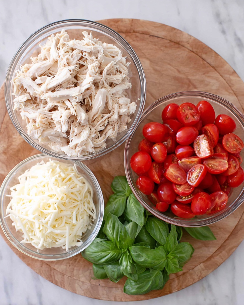 The image shows three clear glass bowls arranged on a wooden round board, on a white marbled texture surface. The largest bowl at the top left is filled with shredded white cooked chicken, with soft texture and light beige color. To its right, there is a medium bowl containing bright red cherry tomatoes, many sliced in half, showing their juicy interior. Below and to the left of the tomatoes, a smaller bowl holds finely shredded white mozzarella cheese. Next to the cheese, on the board, there is a small bunch of fresh green basil leaves with smooth texture and deep green shade. Photo taken with an iphone --ar 4:5 --v 7