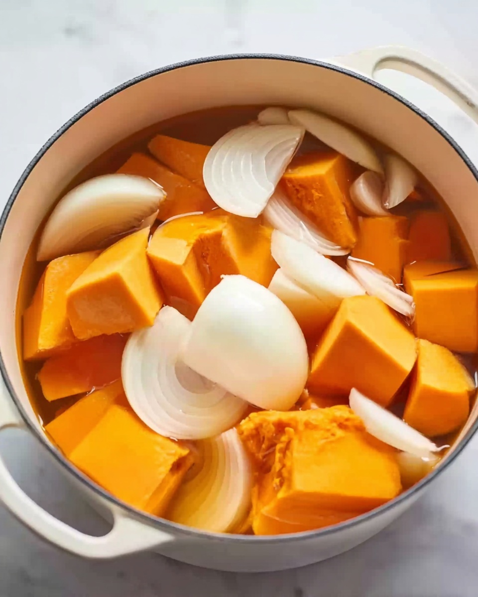 The image shows a white pot filled with large, orange chunks of squash or pumpkin and thick slices of white onion floating in clear water. The orange pieces are mostly cubic and cover the bottom and middle layers of the pot, while the white onion slices, some curved and some in segments, rest on top and mixed among the orange chunks. The white pot sits on a white marbled surface. photo taken with an iphone --ar 4:5 --v 7