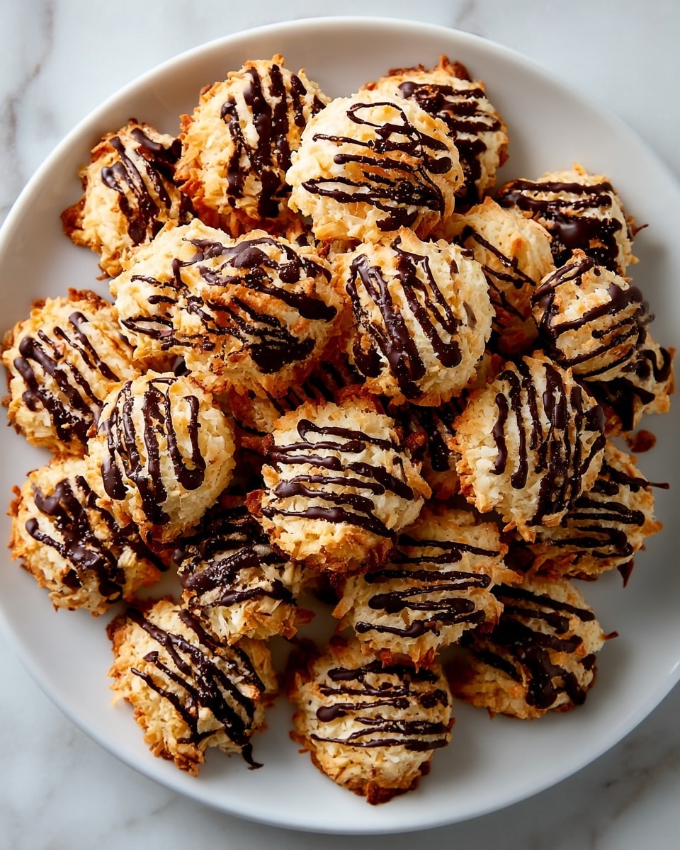 A white plate holds many small, round cookies with a rough texture from toasted coconut. Each cookie is golden brown with a crispy look and is topped with thin, dark chocolate lines drizzled unevenly in a zigzag pattern. The cookies are placed closely together, covering most of the plate, which sits on a white marbled surface. photo taken with an iphone --ar 4:5 --v 7